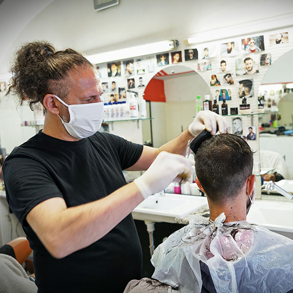 Male Barber cutting a man's hair wearing masks