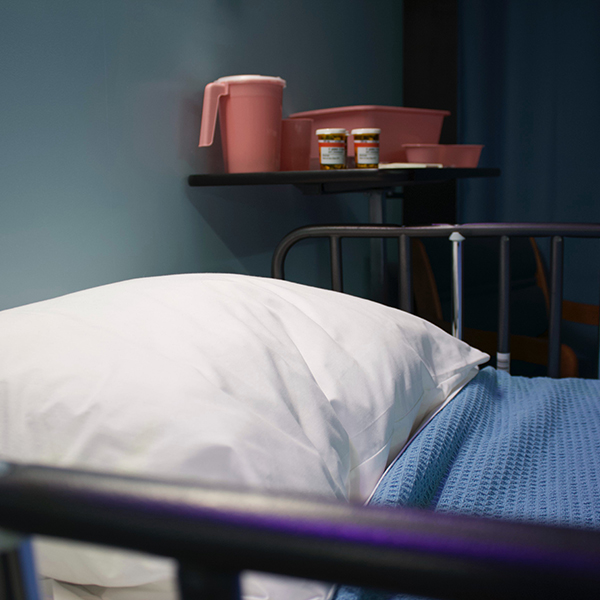 Hospital bed with pillow and a blue blanket