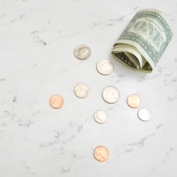 One dollar American bills with coins on a marble table